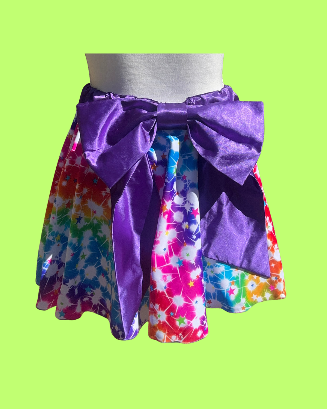 Colorful tie-dye running skirt with a large purple bow on a green background