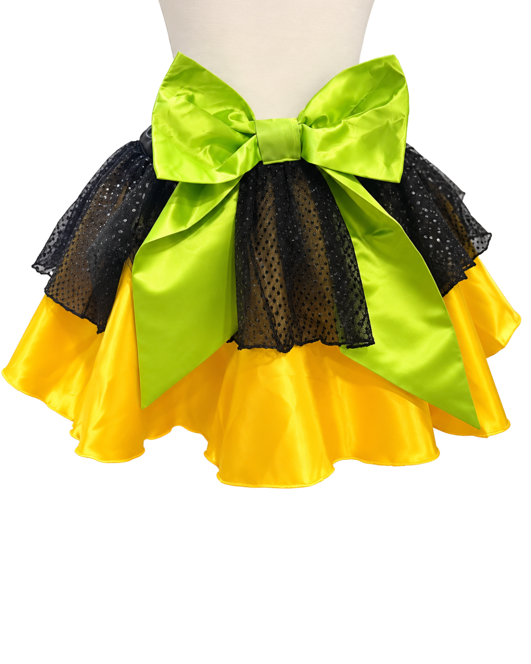 A three-layered ruffled tutu skirt on a mannequin torso, featuring a large lime green satin bow at the waist, a black mesh middle layer, and a bright yellow satin bottom layer.