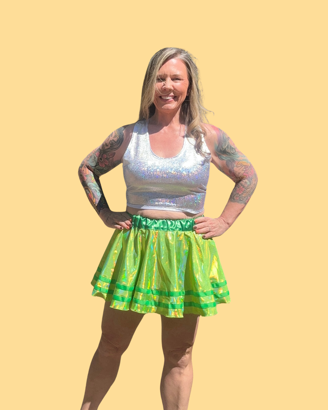 Person wearing a silver sequin top and green running skirt against a yellow background