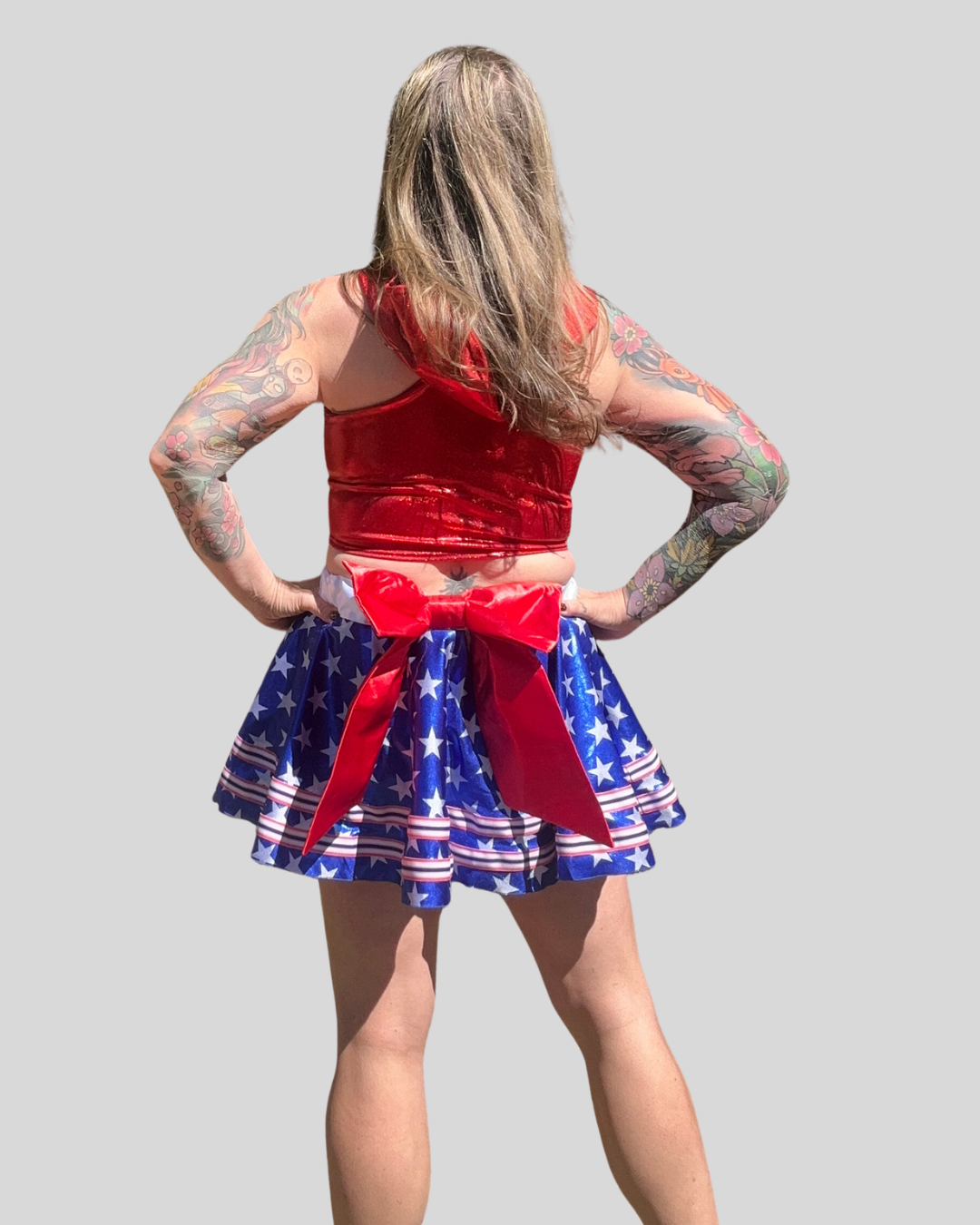 Person wearing a red top and blue and white running skirt with a red bow on a gray background