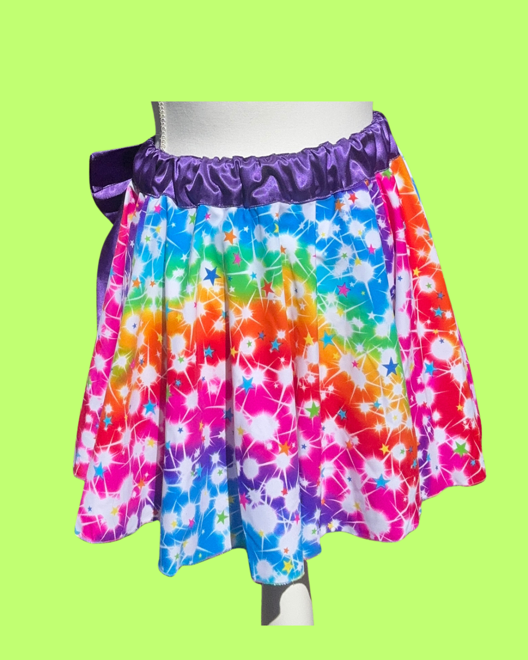 Colorful tie-dye pride running skirt with a purple waistband on a green background