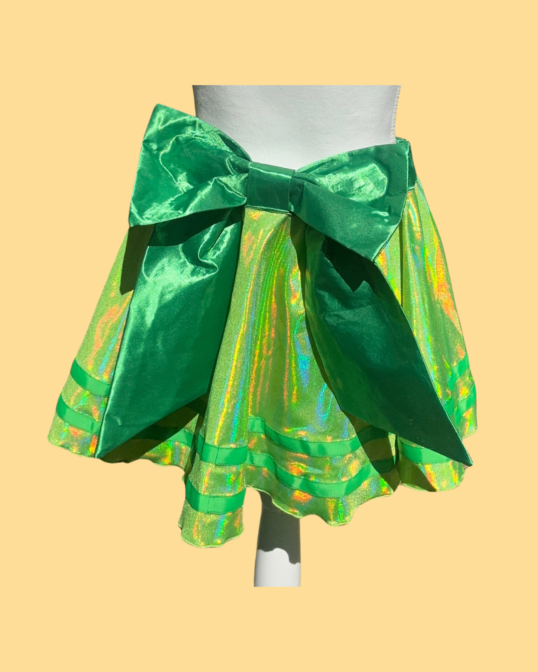 Green margarita running skirt with a large bow on a mannequin against a yellow background