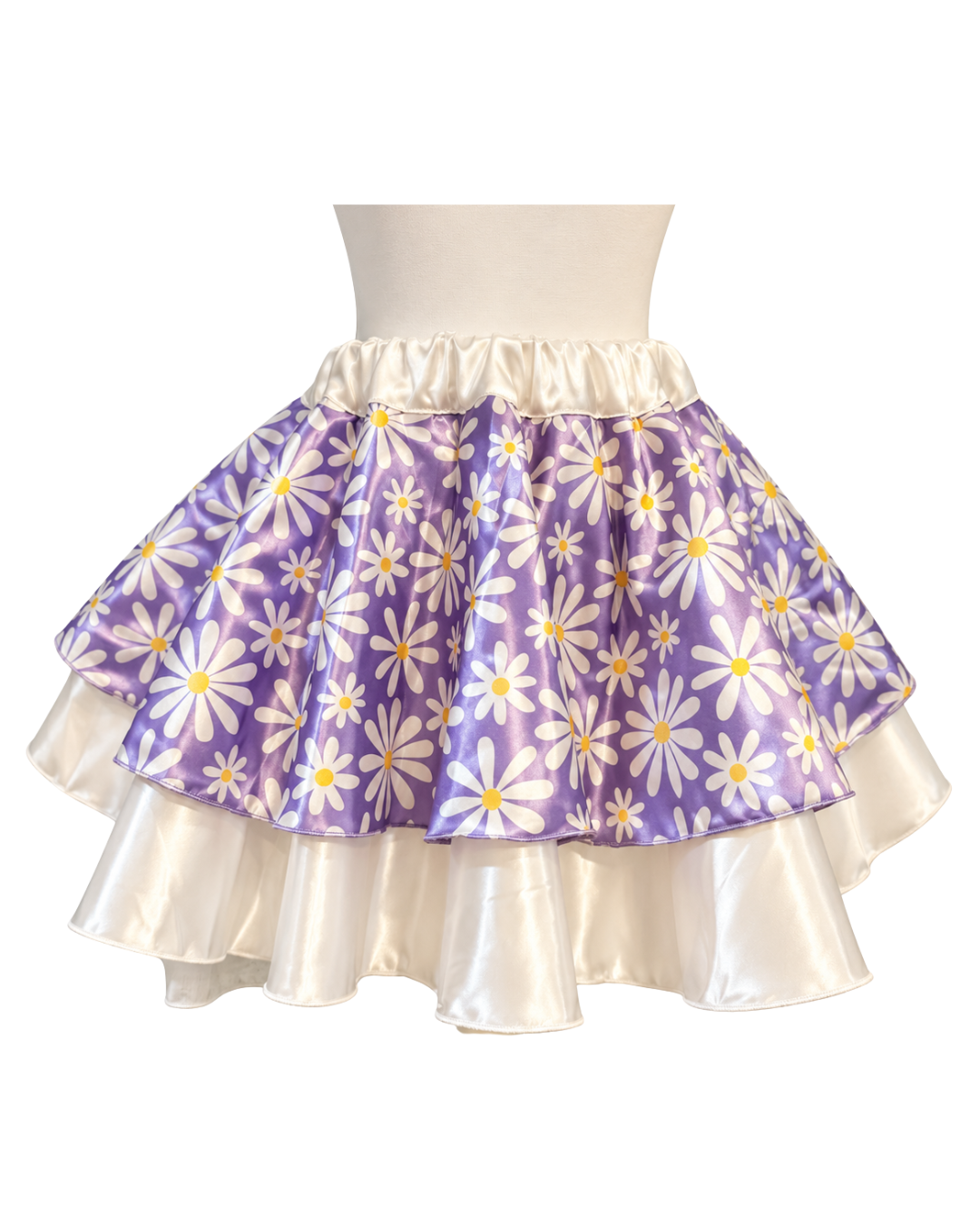 A tiered ruffle skirt with a purple and white daisy floral print on the outer layer and a shiny cream inner layer, displayed on a mannequin torso against a white background.